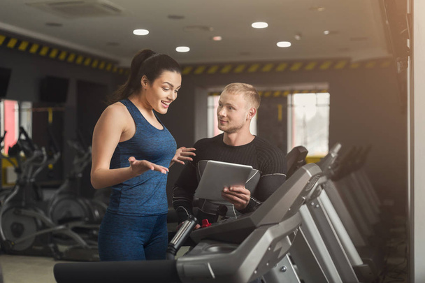 Fitness coach helps woman on elliptical trainer - Photo, Image