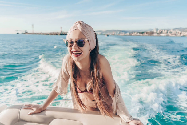an attractive girl in sunglasses swims on her white yacht on the eagle, laughs, enjoys sea voyage - Fotó, kép