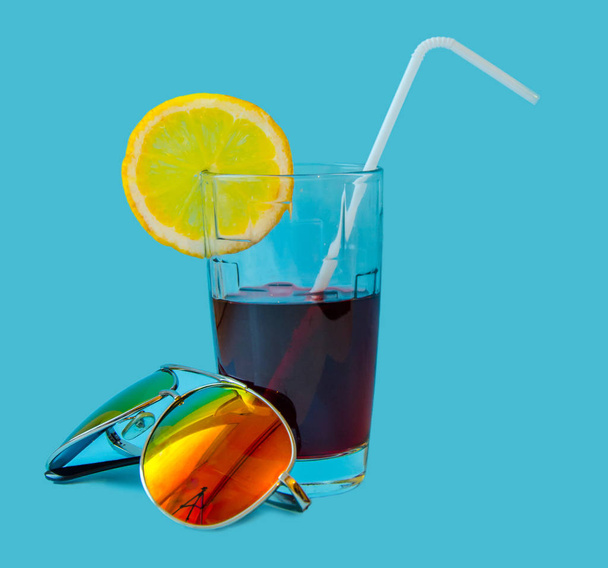 Fresh Juice glass with a straw slice of yellow lemon and sunglasses on a blue background. Fashion pastel summer design style concept - Φωτογραφία, εικόνα