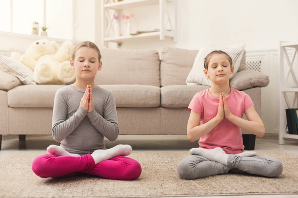 Kleine Mädchen trainieren gemeinsam Yoga im Haus - Foto, Bild