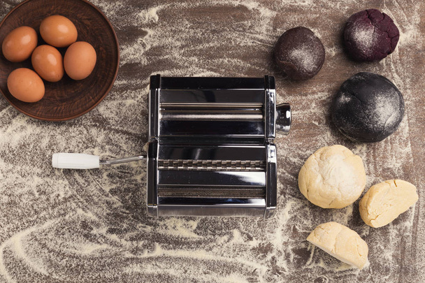 Μηχανή ζυμαρικών και πολύχρωμο ζύμη στο τραπέζι της κουζίνας - Φωτογραφία, εικόνα