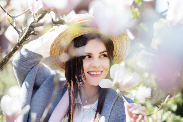Szabadtéri portré fiatal gyönyörű divatos hölgy pózol közel virágzó fa. - Fotó, kép