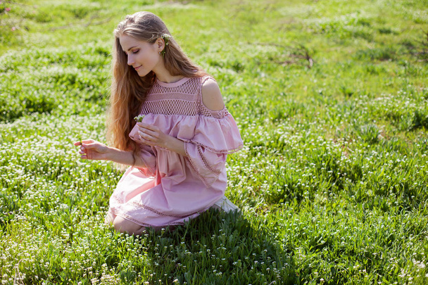 blonde girl in pink dress is collecting flowers in the garden - Fotó, kép
