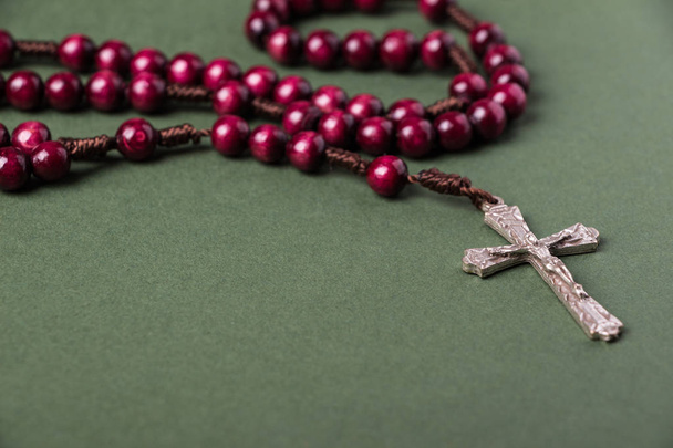 Ροζ Rosary σε πράσινο φόντο με χώρο για τη σύνταξη του Χριστιανικού σταυρού. - Φωτογραφία, εικόνα