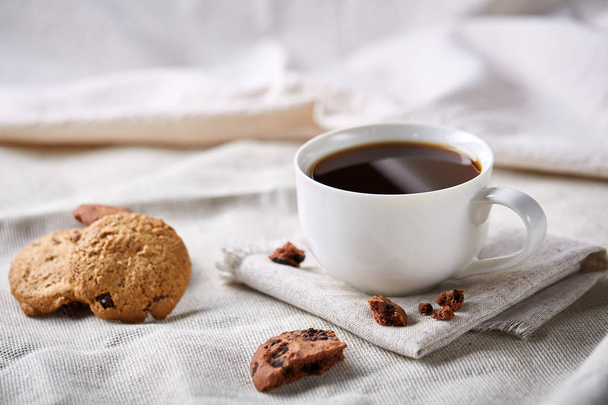 Morning coffee in white cup, chocolate chips cookies on cutting board close-up, selective focus - Foto, Bild