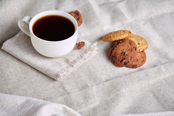 Morning coffee in white cup, chocolate chips cookies on cutting board close-up, selective focus - Φωτογραφία, εικόνα