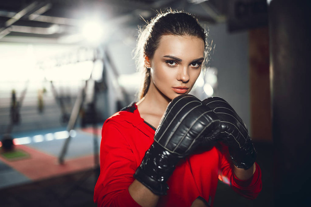 Fit slim young beautiful brunette woman boxing in sportswear. Dark dim light. - Foto, afbeelding