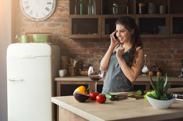 Femme heureuse parlant au téléphone dans la cuisine de la maison
 - Photo, image