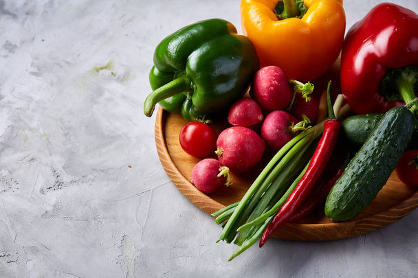 Houten plaat met groenten voor een vegetarische salade op wit gestructureerde achtergrond, close-up, selectieve aandacht - Foto, afbeelding