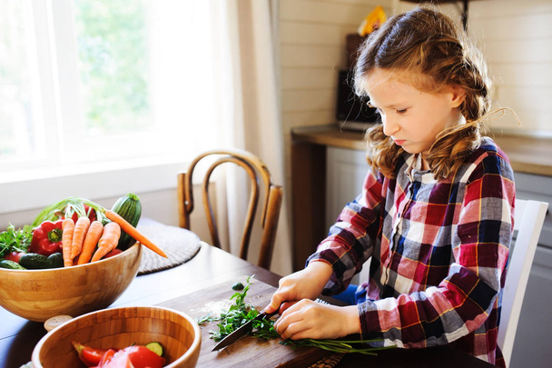 8 years old child girl help mom to cook vegetable salad at home. Healthy eating, little helper concept - Foto, imagen