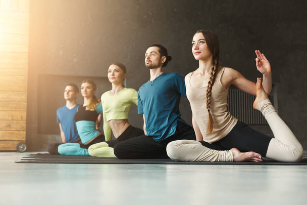 Jeunes femmes et hommes en cours de yoga, pose de sirène étirant
 - Photo, image