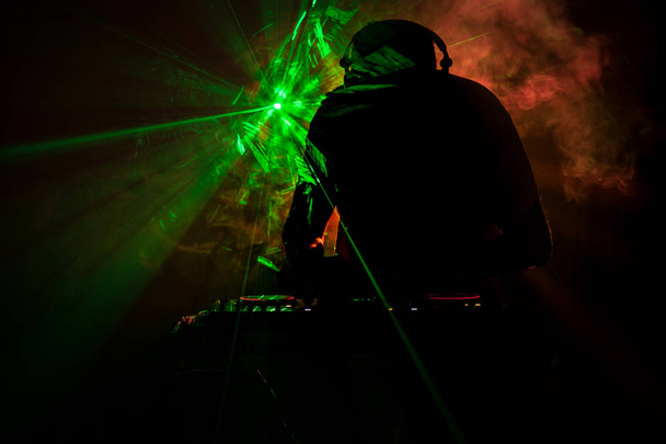 DJ Spinning, Mixing, and Scratching in a Night Club, Manos de dj ajustar varios controles de pista en la cubierta de dj, luces estroboscópicas y niebla, o Dj mezcla la pista en el club nocturno en la fiesta. Enfoque selectivo
 - Foto, imagen