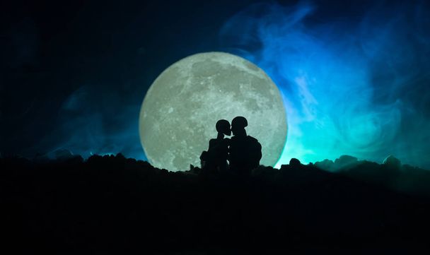 Silhouette of couple kissing under full moon. Guy kiss girl hand on full moon silhouette background. Valentine`s day decor concept. Silhouette of loving couple kissing against the full moon - Photo, Image