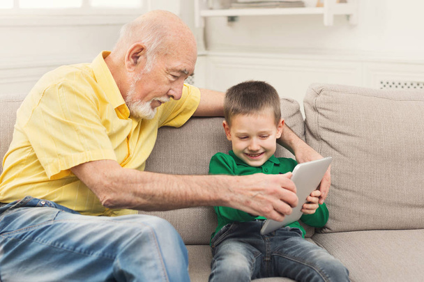 Grandfather taking touch pad from child - Photo, Image