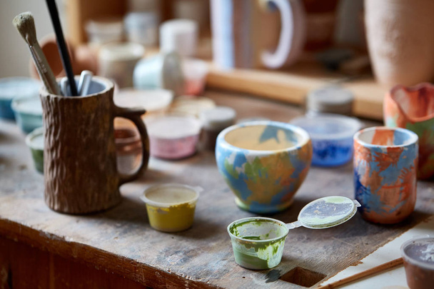 Close-up of various paint mugs and brushes in holder on worktop, selective focus, side view. - Foto, immagini