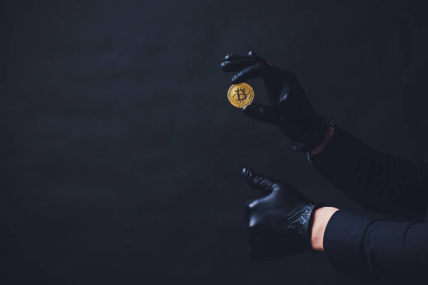 Bitcoins placed on arm Hands in black gloves show symbol. Isolated on black background - Foto, imagen