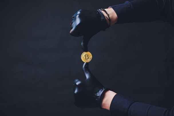 Bitcoins placed on arm Hands in black gloves show symbol. Isolated on black background - Фото, зображення