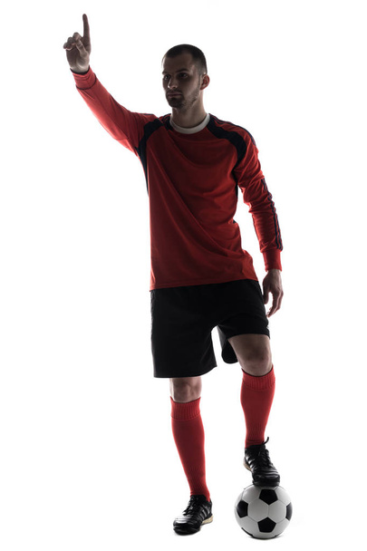 Silhouet van de jonge voetballer wees met vinger met voetbal geïsoleerd op witte achtergrond - Foto, afbeelding