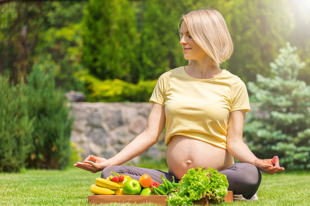 Pregnant woman practicing meditation and relaxation in nature - Photo, image