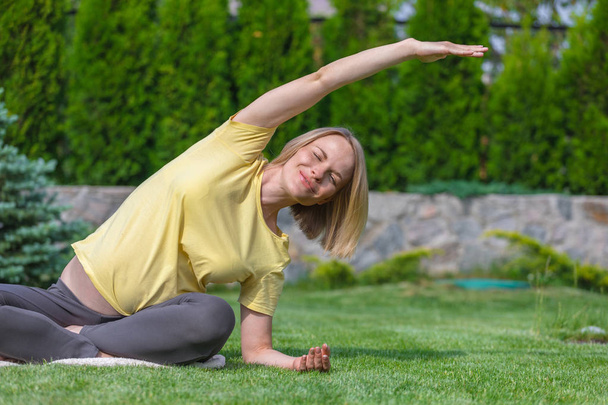 Beautiful pregnant woman doing prenatal yoga on nature. - Photo, Image