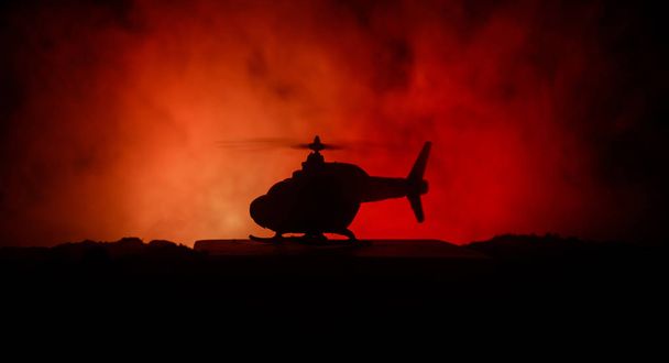 Silhouette di elicottero militare pronto a volare dalla zona di conflitto. Filmato notturno decorato con elicottero che inizia nel deserto con nebbia tonica retroilluminata. Focus selettivo
. - Foto, immagini