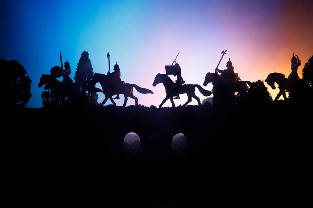 Middeleeuwse slag scène op de brug met de cavalerie en infanterie. Silhouetten van figuren als afzonderlijke objecten, strijd tussen krijgers op donker getinte mistige achtergrond. Nachtbeeld. - Foto, afbeelding