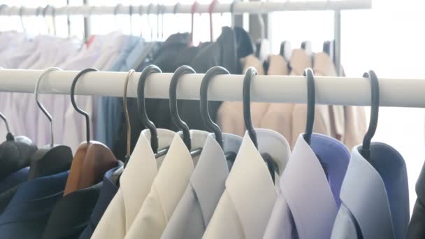 Verschillende zakelijke kleding, met inbegrip van shirts en pakken op een hanger in winkel - Video