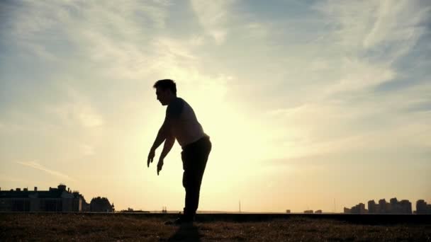 Slow-motion - jonge mannelijke Parkour tricker jumper presteert geweldig flips voor de zon - Video