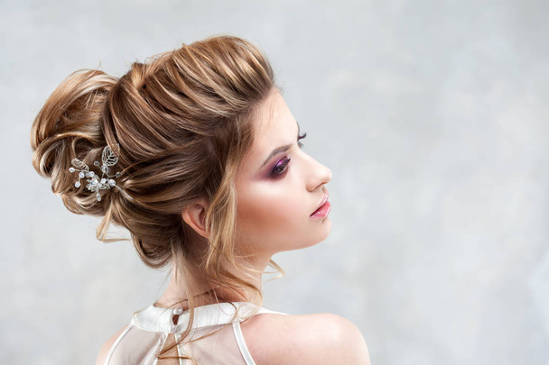 Young beautiful bride with an elegant high hairdo. Wedding hairstyle with the accessory in her hair - Foto, immagini