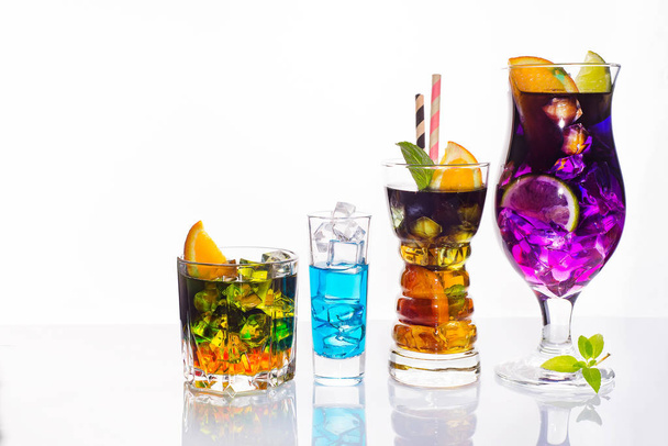 Ποικιλία από πολύχρωμες εορταστικά ποτά, αλκοολούχα ποτά και κοκτέιλ στο κομψό γυαλιά σε λευκό φόντο με αντίγραφο χώρου - Φωτογραφία, εικόνα