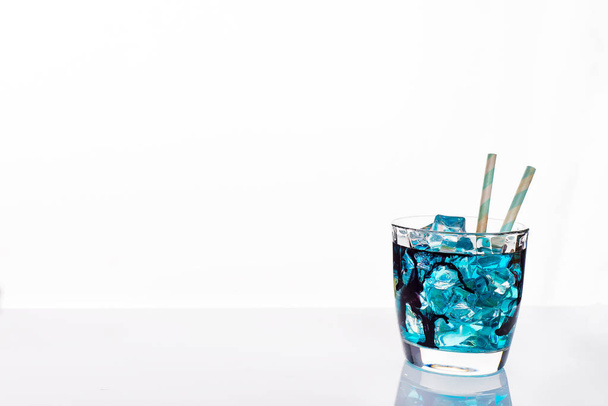 Προήλθε το ποτήρι κοκτέιλ με μπλε οινοπνευματώδες ποτό, γκρο πλαν, απομονωμένα σε λευκό. Πρότυπο σχεδίασης με δείγμα κειμένου - Φωτογραφία, εικόνα