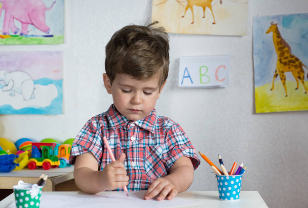 Дошкільнята вчаться писати і читати. Креативний малюк грає і вивчає кольори, форми і розміри за столом у школі
. - Фото, зображення