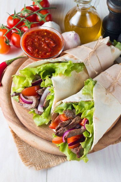Photo of Mexican sandwich food, burrito, fajita, tacos, wrap made of tortilla, beef, chicken, fresh vegetables on rustic wooden background. Fast food concept. Healthy lunch snack. Copy space.  - Photo, Image