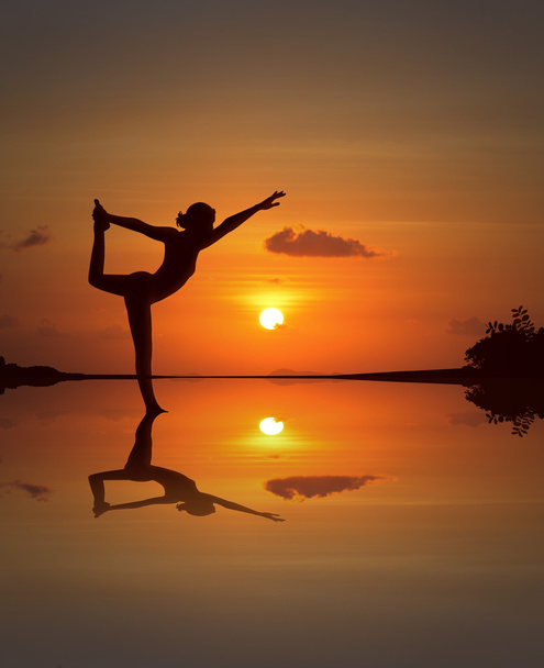 Silhouette of a beautiful Yoga woman in mirrored sunset beach - Fotografie, Obrázek