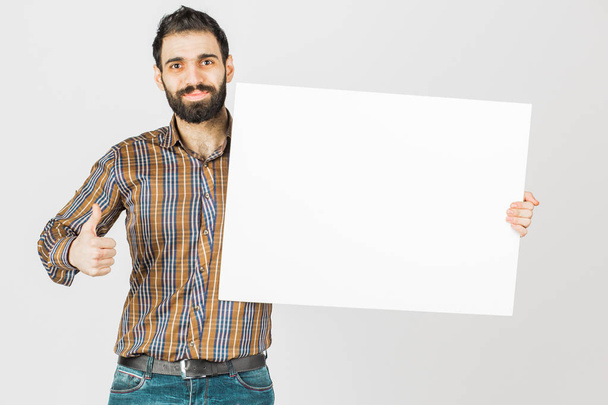 Πορτρέτο ενός γενειοφόρου επιχειρηματία που κατέχουν ένα λευκό κενό πίνακα με χώρο για κείμενο. Απομονωμένα σε λευκό φόντο. - Φωτογραφία, εικόνα