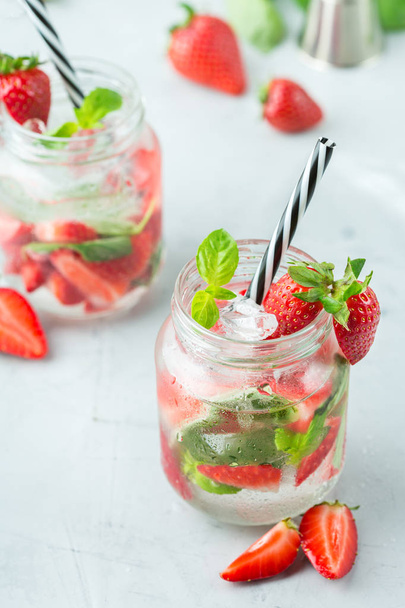 Food and drink, holidays party concept. Cold fresh alcohol beverage mojito cocktail with white rum, soda, red strawberry and basil for refreshment in summer days - Fotografie, Obrázek
