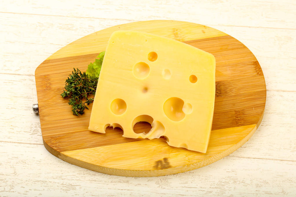 Шматочок сиру над дерев'яною тарілкою
 - Фото, зображення