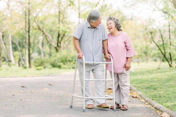 Glückliches Seniorenpaar beim Spaziergang mit Rollator  - Foto, Bild