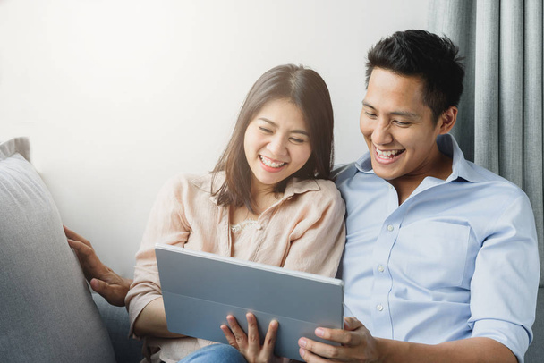 Pareja asiática sonriendo mientras usa tableta digital
 - Foto, imagen