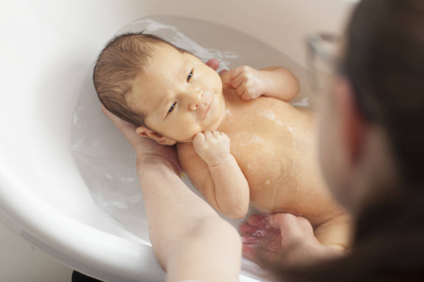  El bebé se está bañando en los brazos de su madre.
. - Foto, Imagen
