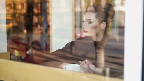 Hora da melancolia. Jovem mulher olhando miserável senta-se no peitoril da janela e bebe lentamente café
. - Filmagem, Vídeo