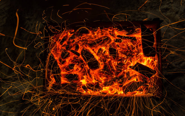 parlak turuncu bir kamp ateşi uzun pozlama ve için için yanan kömürlerin üzerinde gelen kıvılcım. Dynamics satırları izlemeler. - Fotoğraf, Görsel