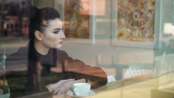 Hora da melancolia. Jovem mulher olhando miserável senta-se no peitoril da janela e bebe lentamente café
. - Filmagem, Vídeo
