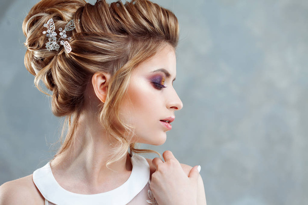 Young beautiful bride with an elegant high hairdo. Wedding hairstyle with the accessory in her hair - Fotografie, Obrázek