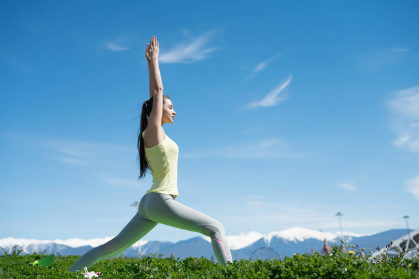 slender young girl doing yoga on green grass on a warm spring day, pacified - Foto, Imagem