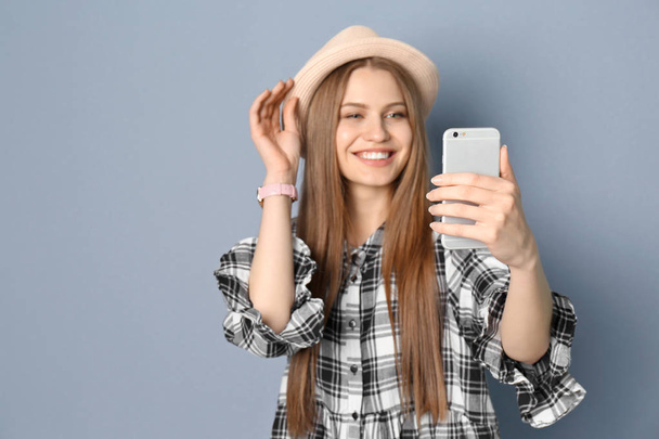 Young beautiful woman taking selfie against grey background - Φωτογραφία, εικόνα