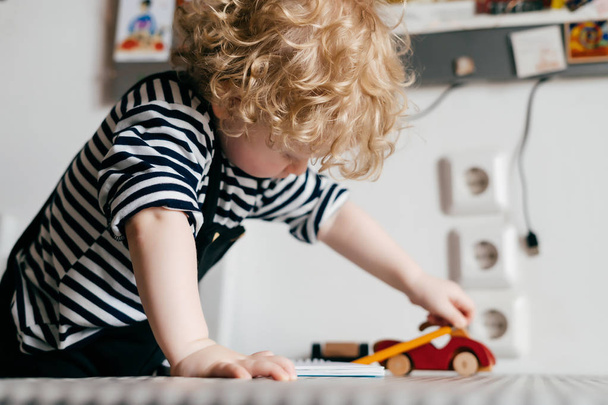 little curly baby boy playing with toy car - Фото, зображення