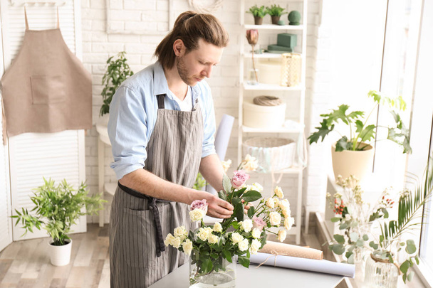 Male florist creating floral composition at workplace - Фото, изображение