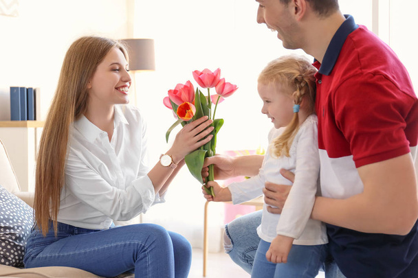 Happy woman receiving flowers from husband and daughter at home. Mother's day celebration - Foto, immagini