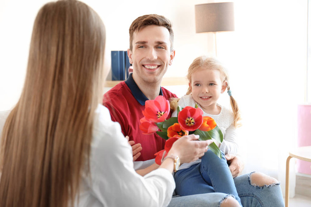 Happy woman receiving flowers from husband and daughter at home. Mother's day celebration - Photo, Image